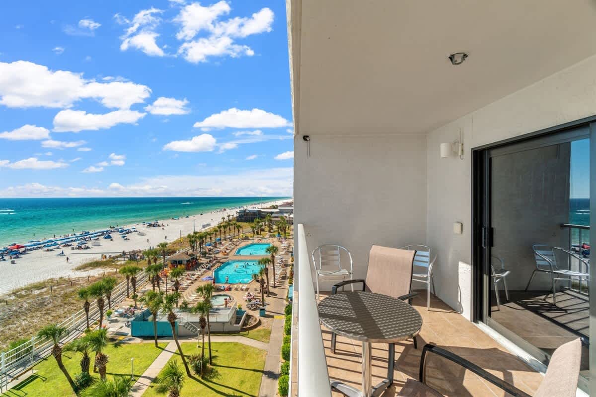The Summit 731 – Ocean view from a balcony featuring table and chairs, overlooking a pool area and sandy beach.