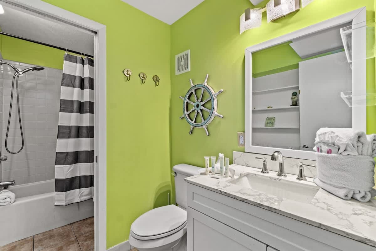 The Summit 731 – Bathroom with green walls, white fixtures, towel storage, and nautical decor.