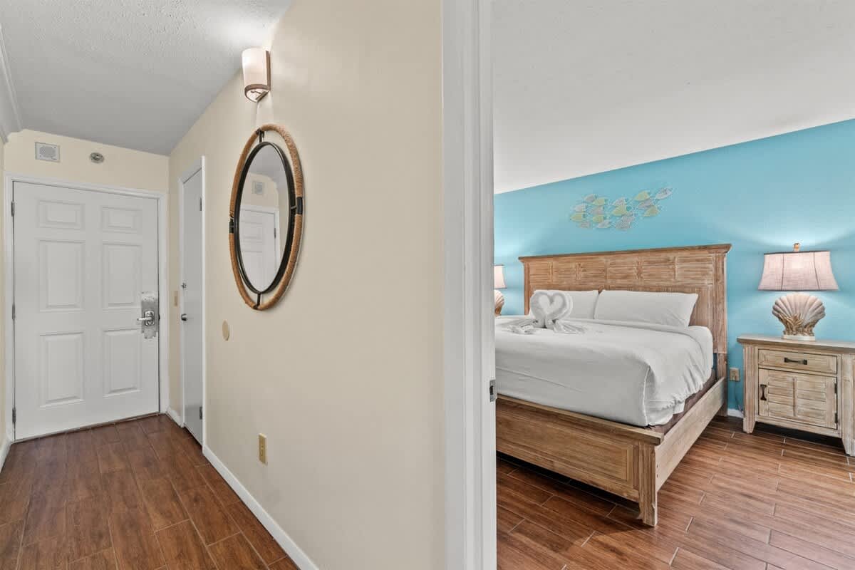 The Summit 731 – Entryway leading to a bedroom with blue accent wall, wooden bed, and decorative lamps.