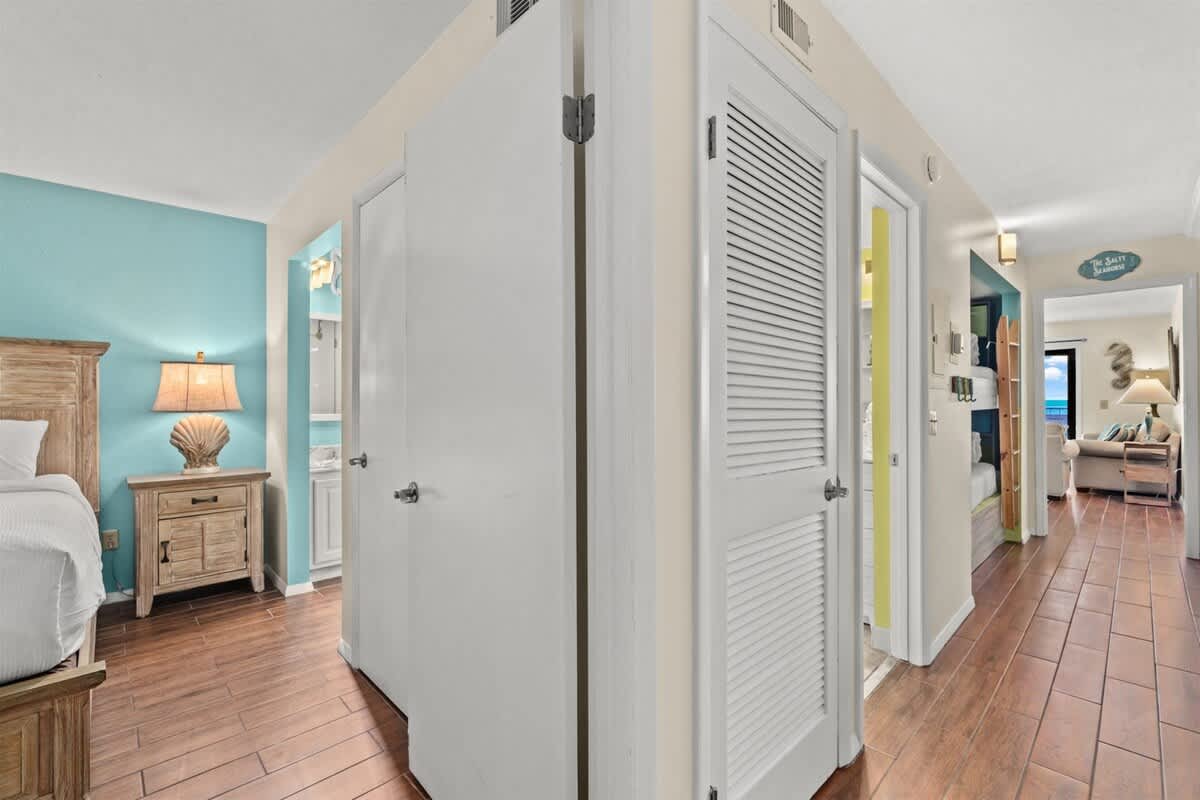 The Summit 731 – Hallway with doors leading to bedrooms, wooden floors, and a view of a living area at the end.