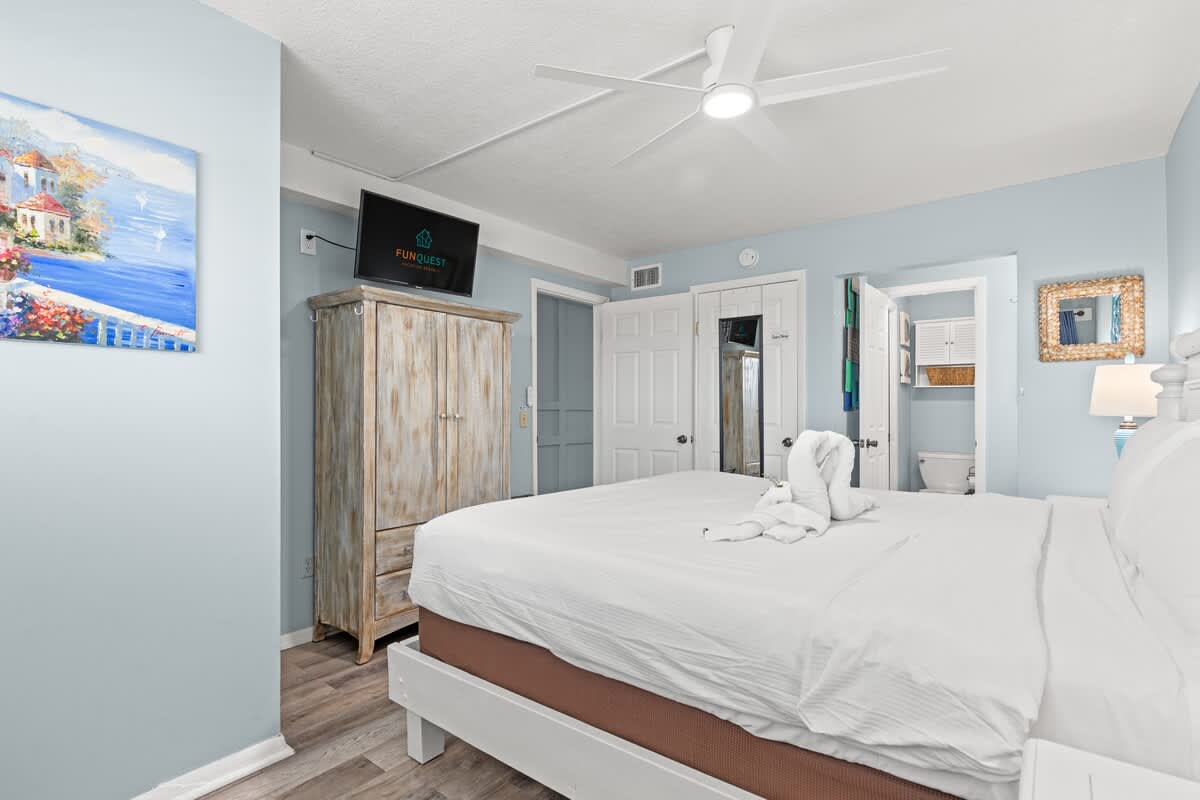 The Summit 712 – Bedroom with a king-size bed, TV, wooden wardrobe, and light blue walls.