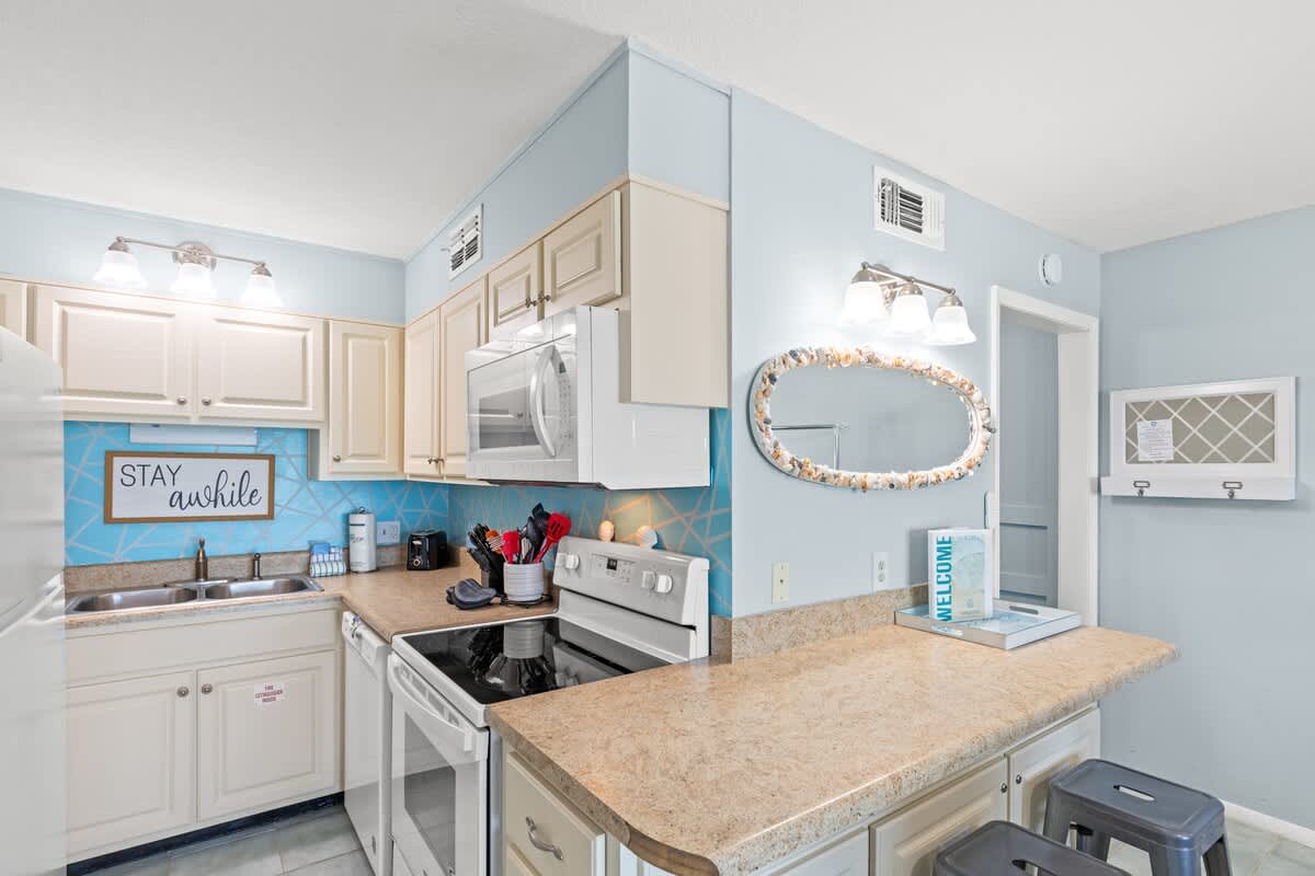 The Summit 712 – Compact kitchen with beige cabinets, blue accent wall, and stainless steel appliances.