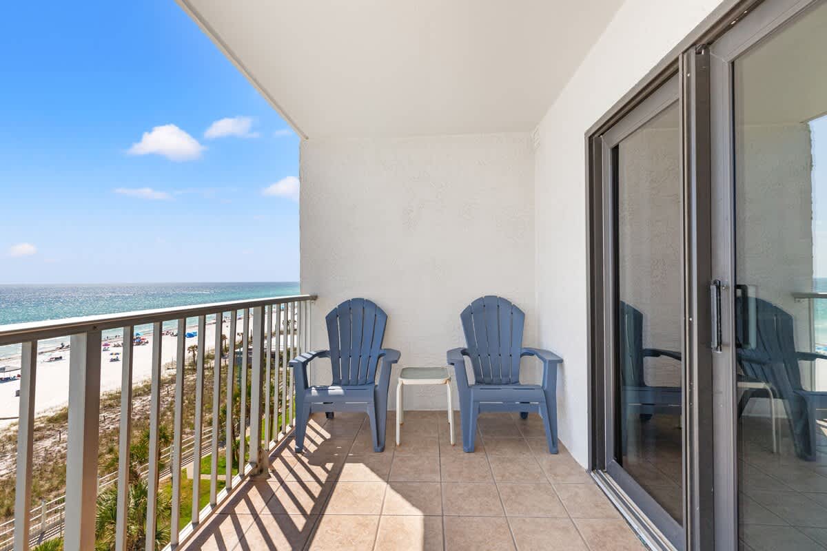 The Summit 712 – Balcony with two blue chairs and a table, overlooking beach and ocean view.