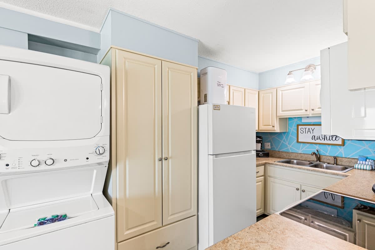 The Summit 712 – Compact kitchen with white appliances, countertop space, and light blue accent wall.