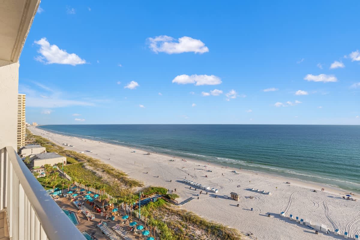 The Summit 1305 – Oceanview from balcony with sandy beach, lounge chairs, and a clear blue sky.