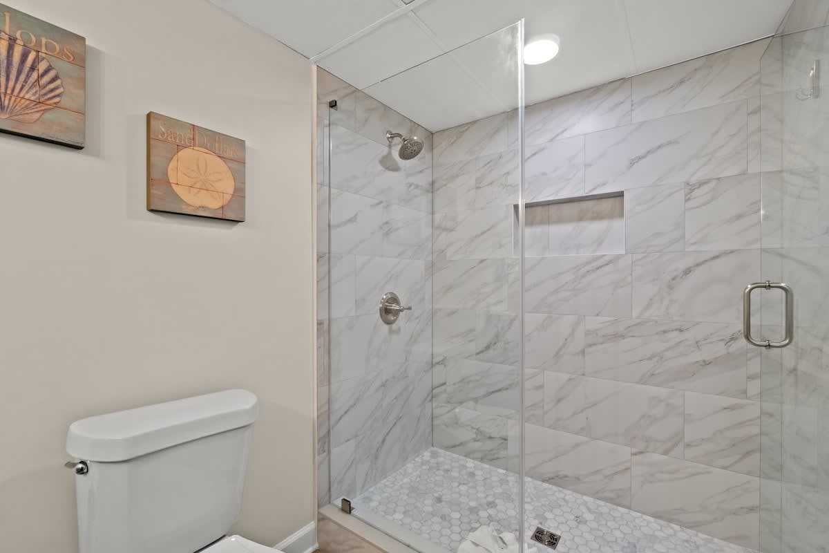Aquavista 804E – Modern bathroom with glass shower, marble tiles, and decorative shell artwork.