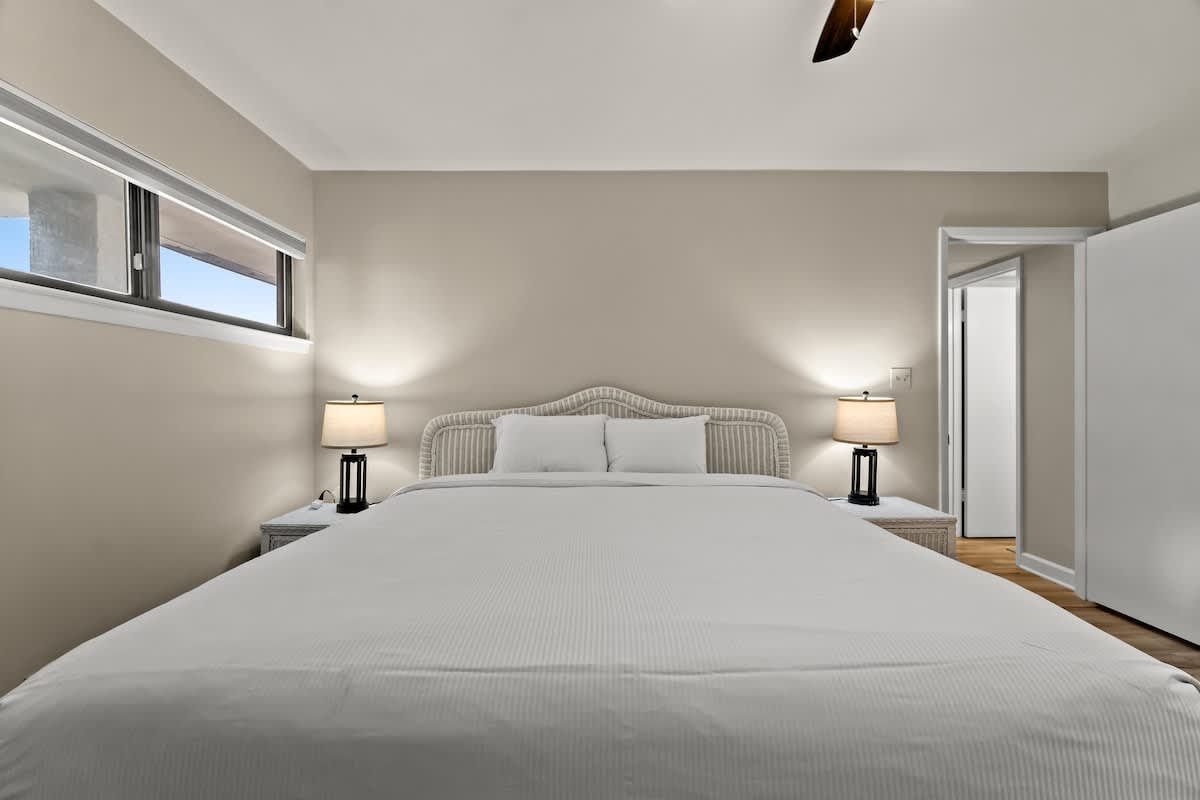 Aquavista 804E – Cozy bedroom featuring a king-sized bed, nightstands, lamps, and a doorway leading to an adjoining room.