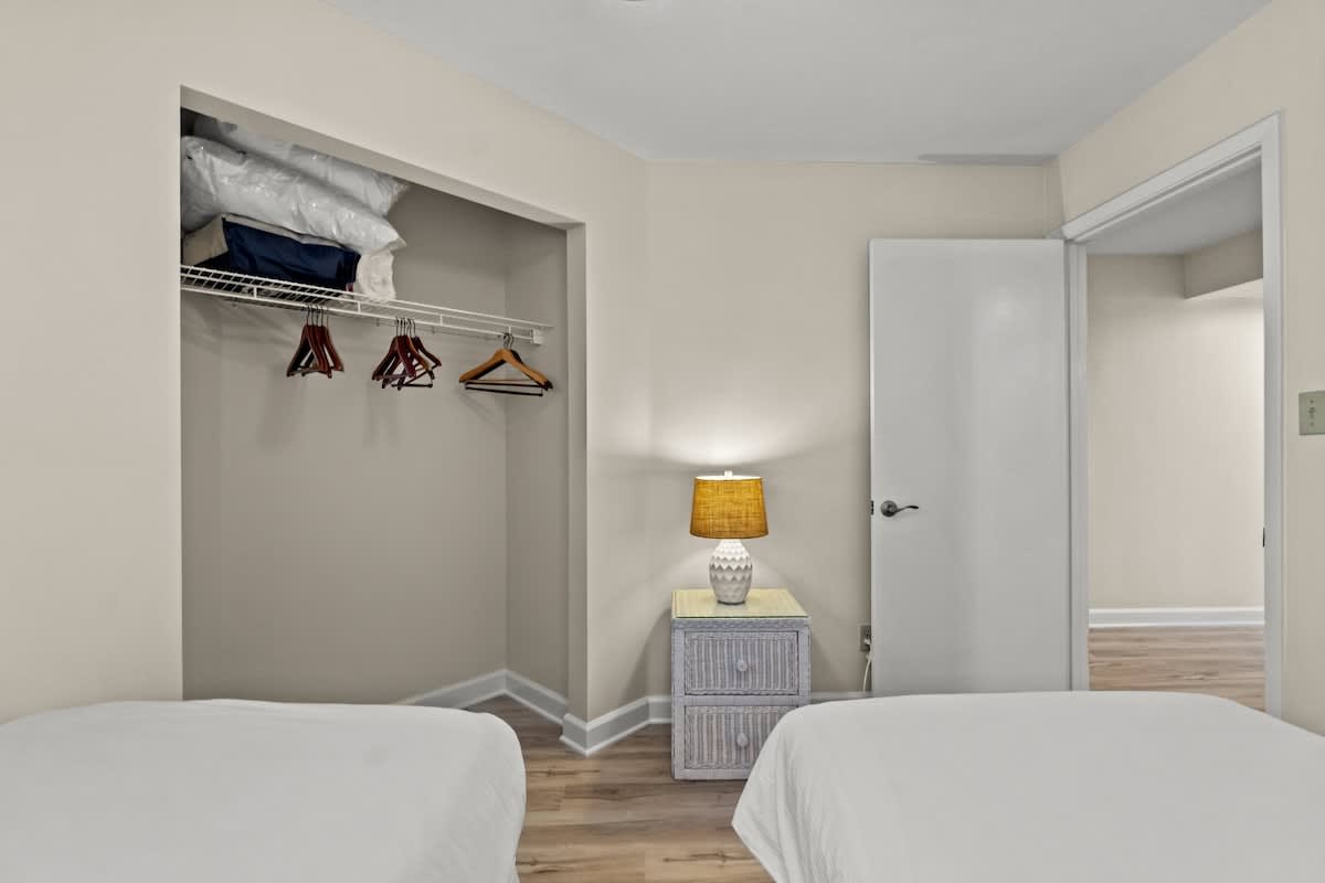Aquavista 804E – Bedroom featuring two beds, a lamp, and an open closet with shelves and hangers.