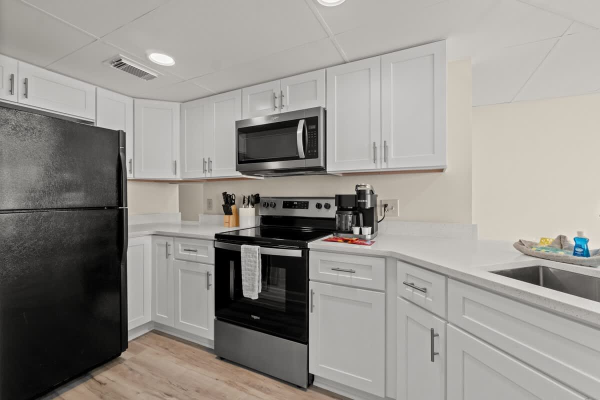 Aquavista 804E – Modern kitchen with white cabinets, black appliances, and quartz countertops.