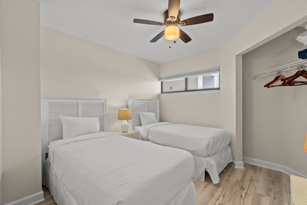 Aquavista 804E – Bedroom with two twin beds, ceiling fan, nightstand, and open closet space.