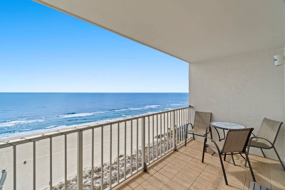The Summit 1213 – Balcony view of beach and ocean, featuring a table and two chairs.