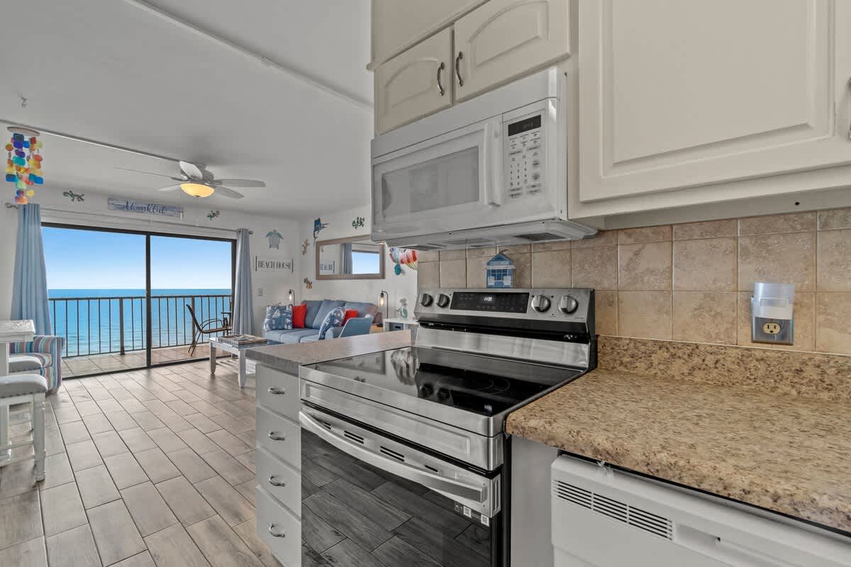 The Summit 1213 – Cozy living area with kitchen, ocean view, seating area, and sliding glass door to balcony.
