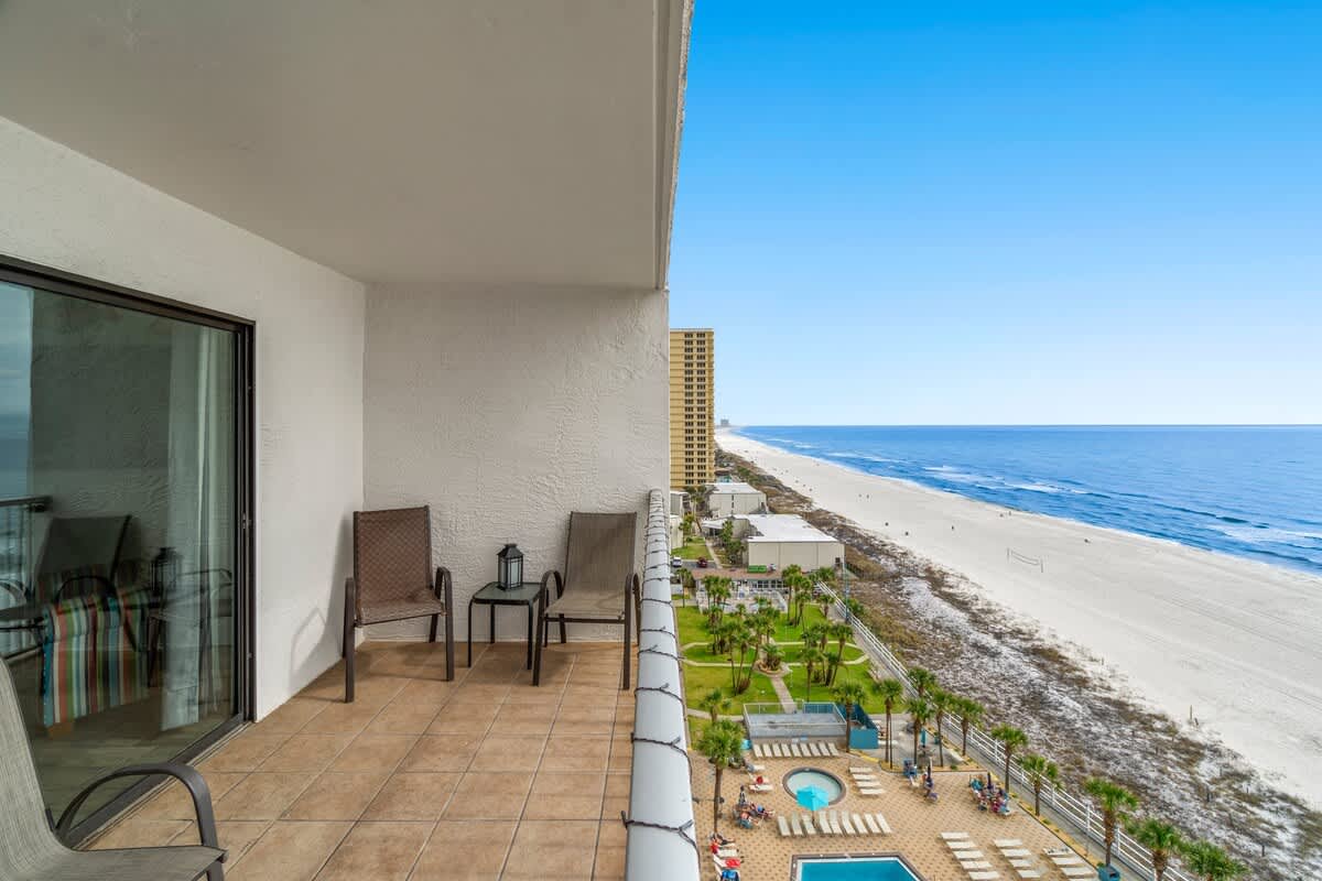 The Summit 1213 – Balcony with two chairs, ocean view, beach, and pool area below.