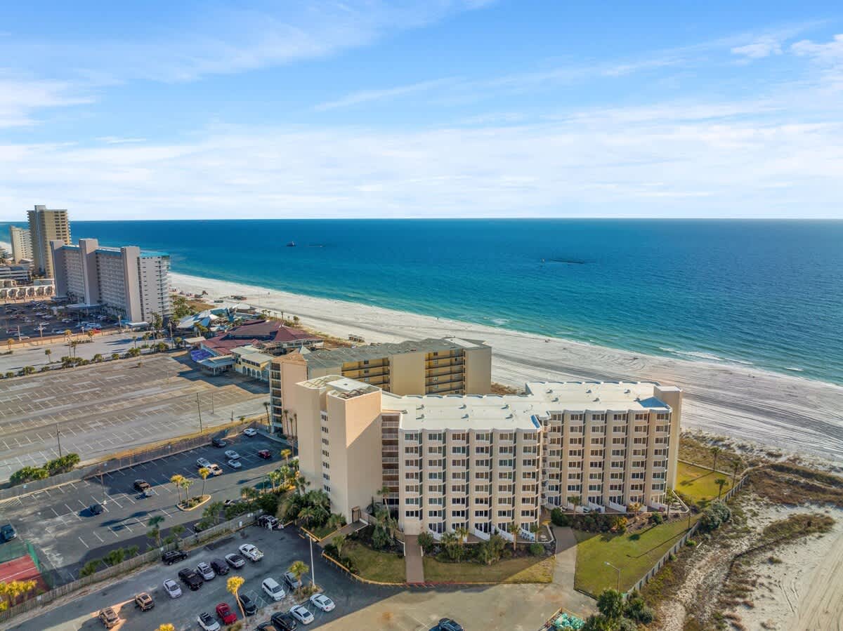 Top Of The Gulf 306 – Beachfront view of a rental building with parking lot and sandy beach.