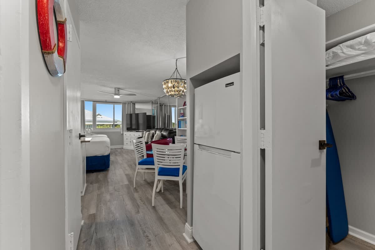 Top Of The Gulf 306 – Interior view of a vacation rental with kitchen, dining area, and a bed visible through the doorway.