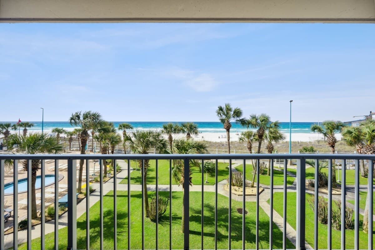 The Summit 307 – View from balcony overlooking beach, palm trees, and pool area.
