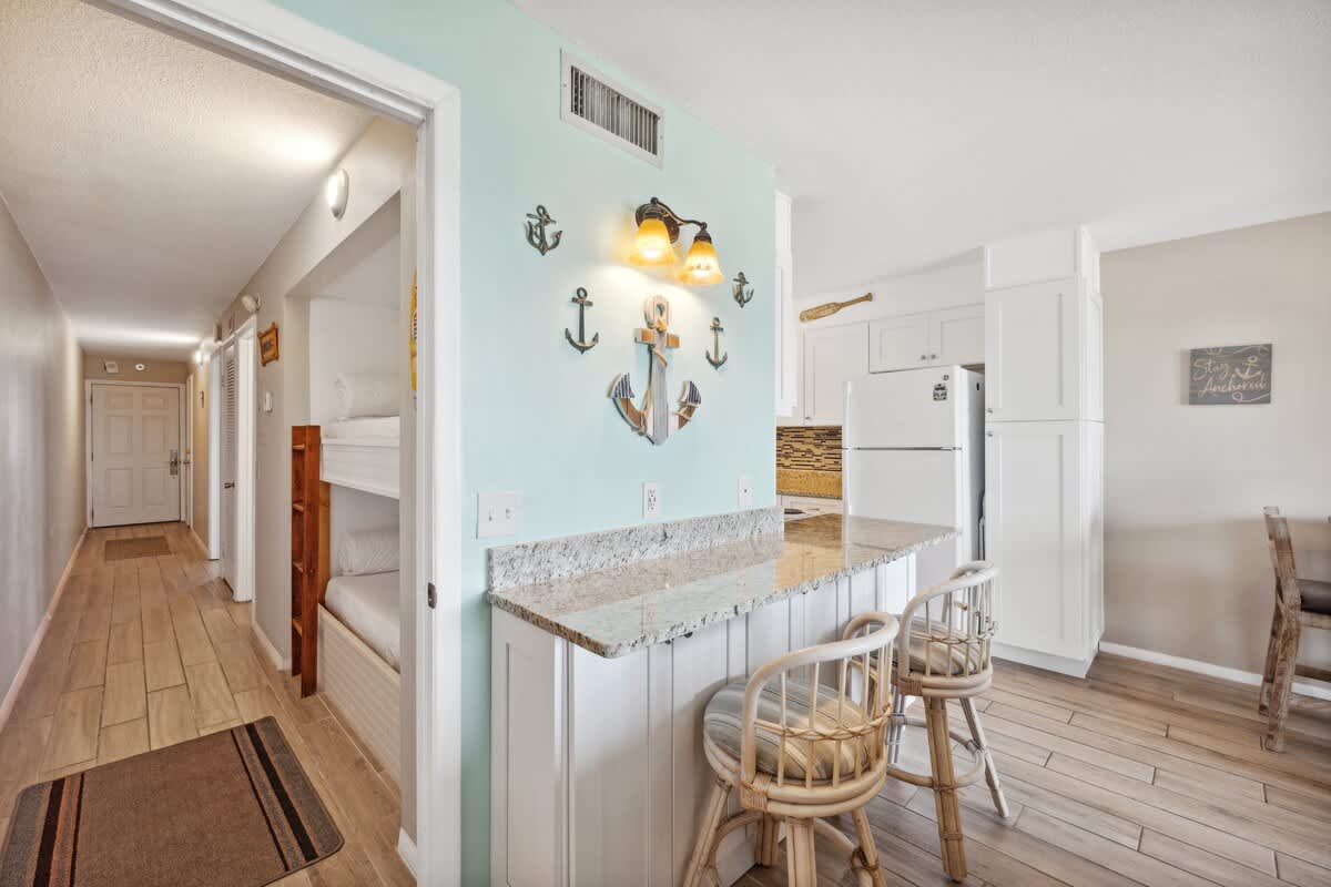 The Summit 307 – Cozy vacation rental kitchen area with barstools, bunk beds, and decorative beach-themed accents.