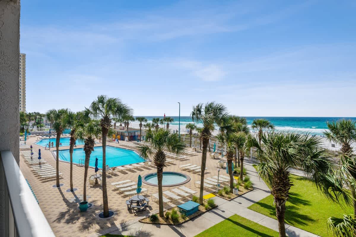 The Summit 307 – View of a swimming pool area with palm trees and ocean in the background.
