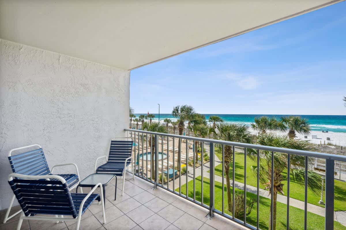 The Summit 307 – Balcony view with two chairs, overlooking beach and palm trees at The Summit 307.