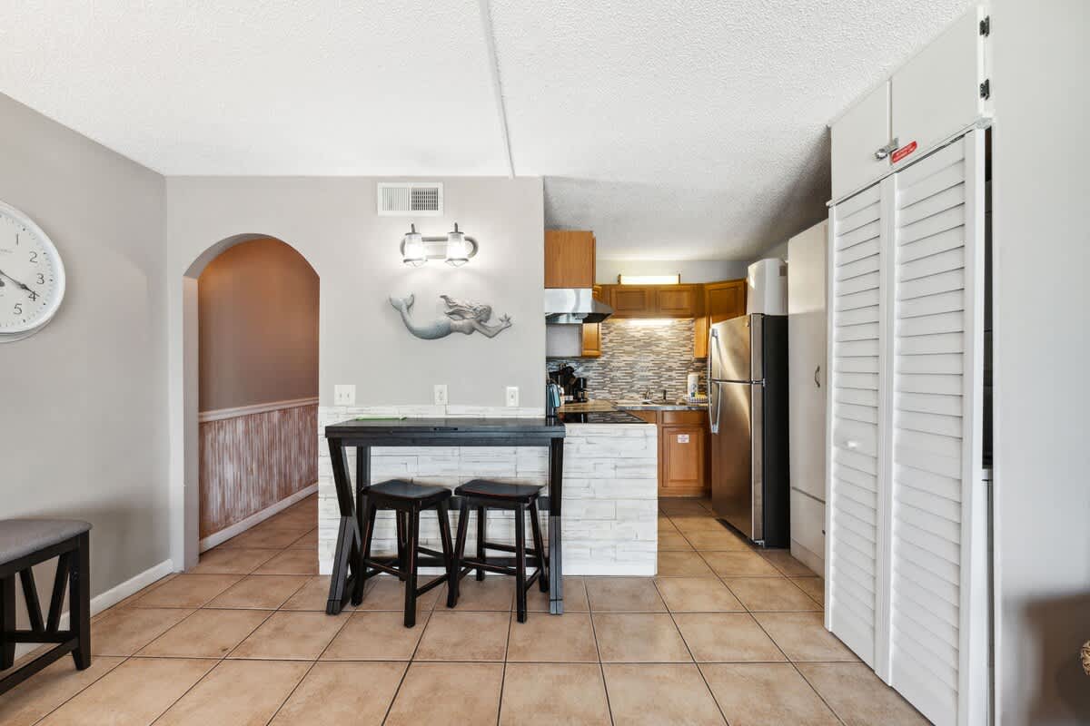 The Summit 817 – View of a kitchen and dining area with a small table and stools, wood cabinetry, and tiled flooring.