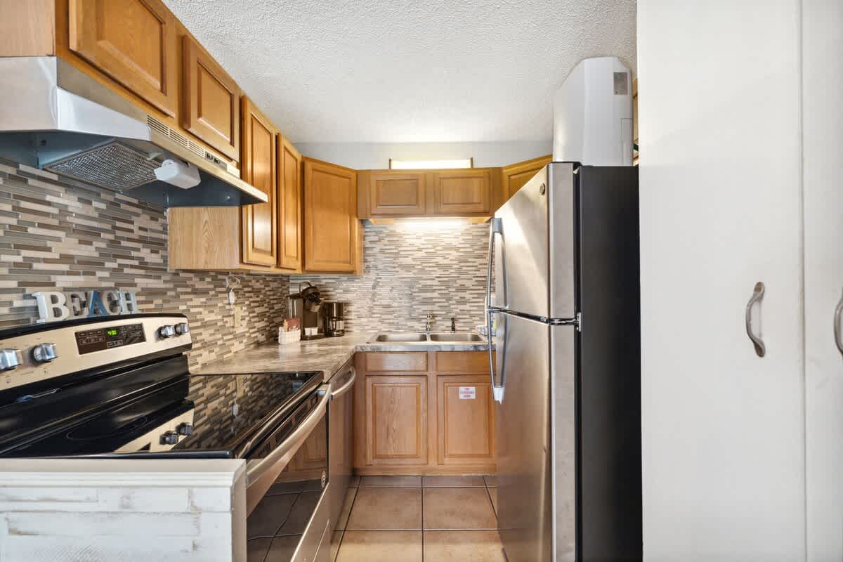 The Summit 817 – Kitchen with stainless steel appliances, wooden cabinets, and a tiled backsplash.