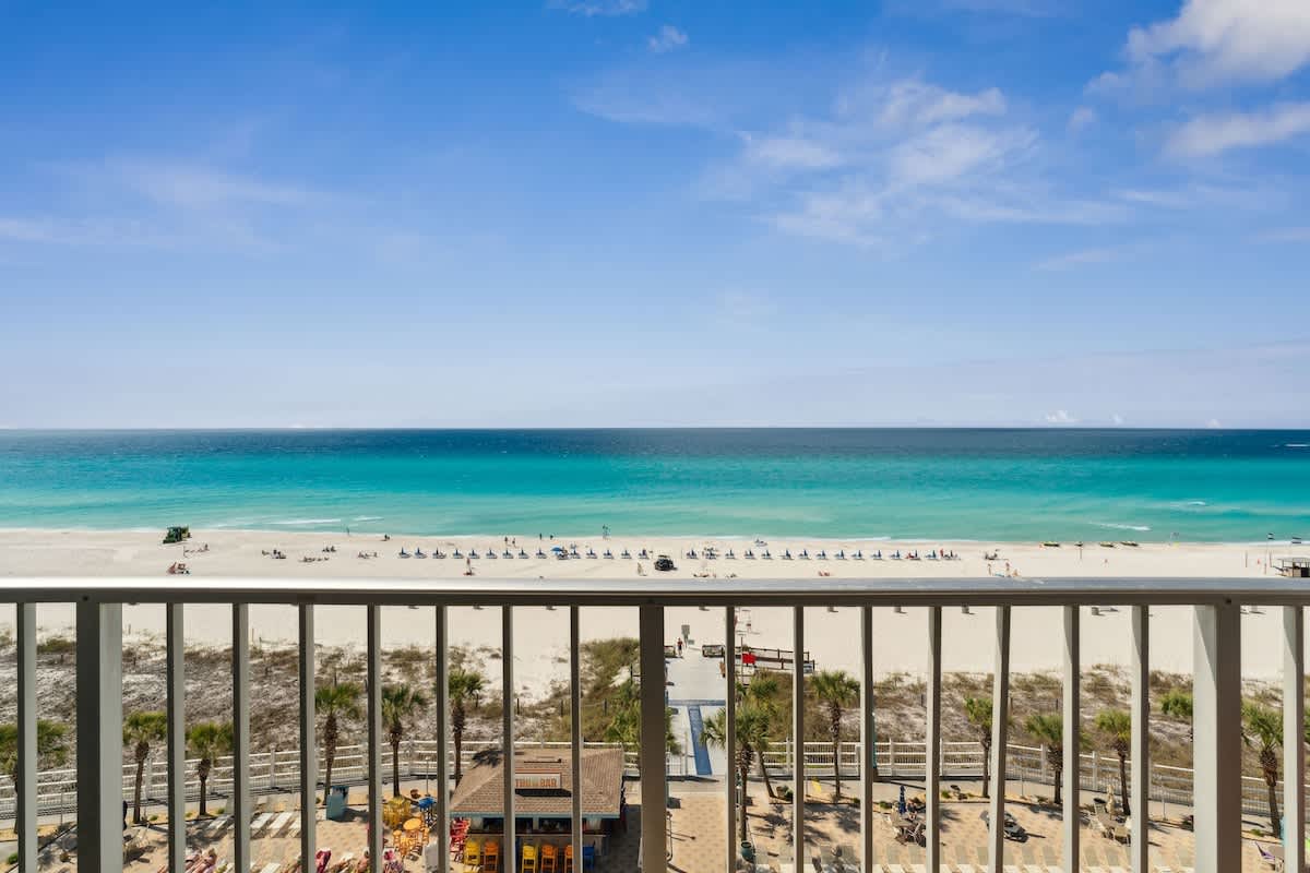 The Summit 817 – Balcony view of sandy beach, turquoise water, and palm trees from The Summit 817.