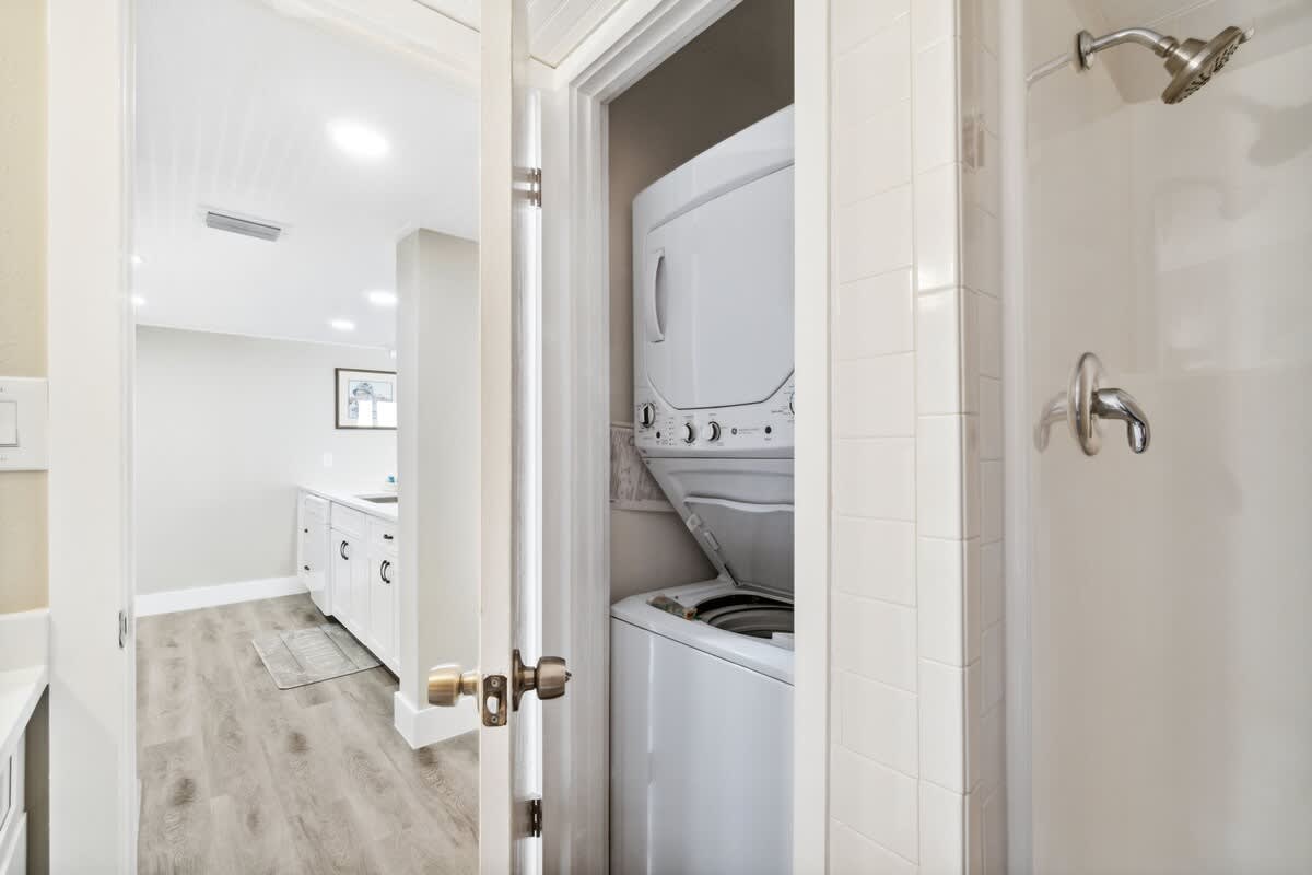 Moondrifter 502 – Laundry area with washer and dryer, adjacent to bathroom with shower, light-colored floors and walls.