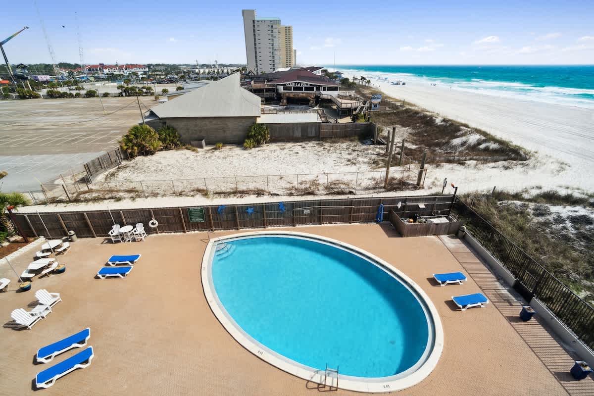Moondrifter 502 – View of an oval pool surrounded by lounge chairs, with sandy beach and ocean in the background.