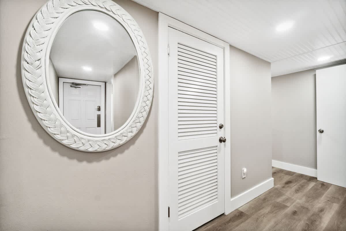 Moondrifter 502 – Entryway with a round mirror, white door, and light-colored wooden flooring.