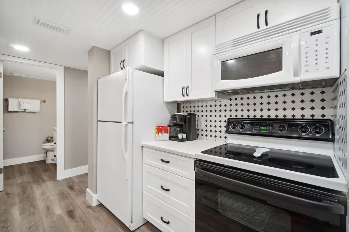 Moondrifter 502 – Compact kitchen with white cabinets, appliances, and a small bathroom visible in the background.