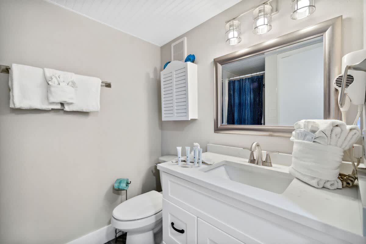 Moondrifter 502 – Modern bathroom featuring a sink, mirror, towels, toiletries, and a shower curtain.