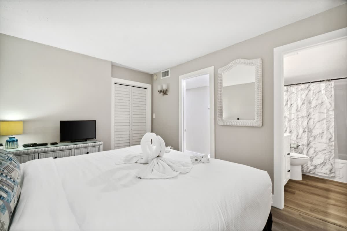 Moondrifter 502 – Bedroom with a queen bed, TV, mirror, and bathroom doorway.