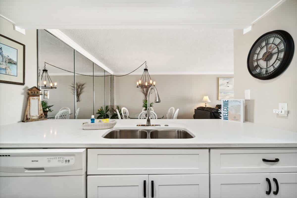 Moondrifter 502 – Open kitchen with white cabinets, sink, and view of living area featuring a chandelier and seating.
