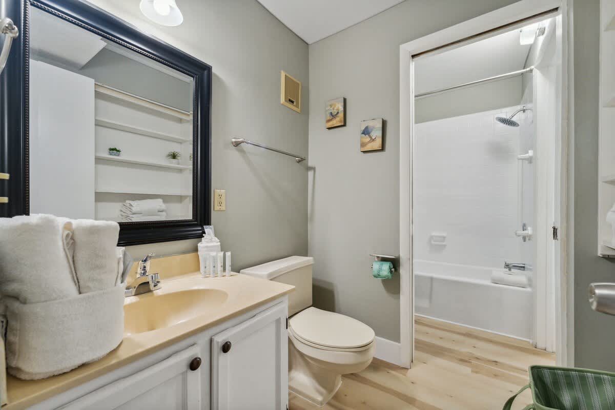 The Summit 1222 – Bathroom with a sink, toilet, shower, and light-colored wood flooring.