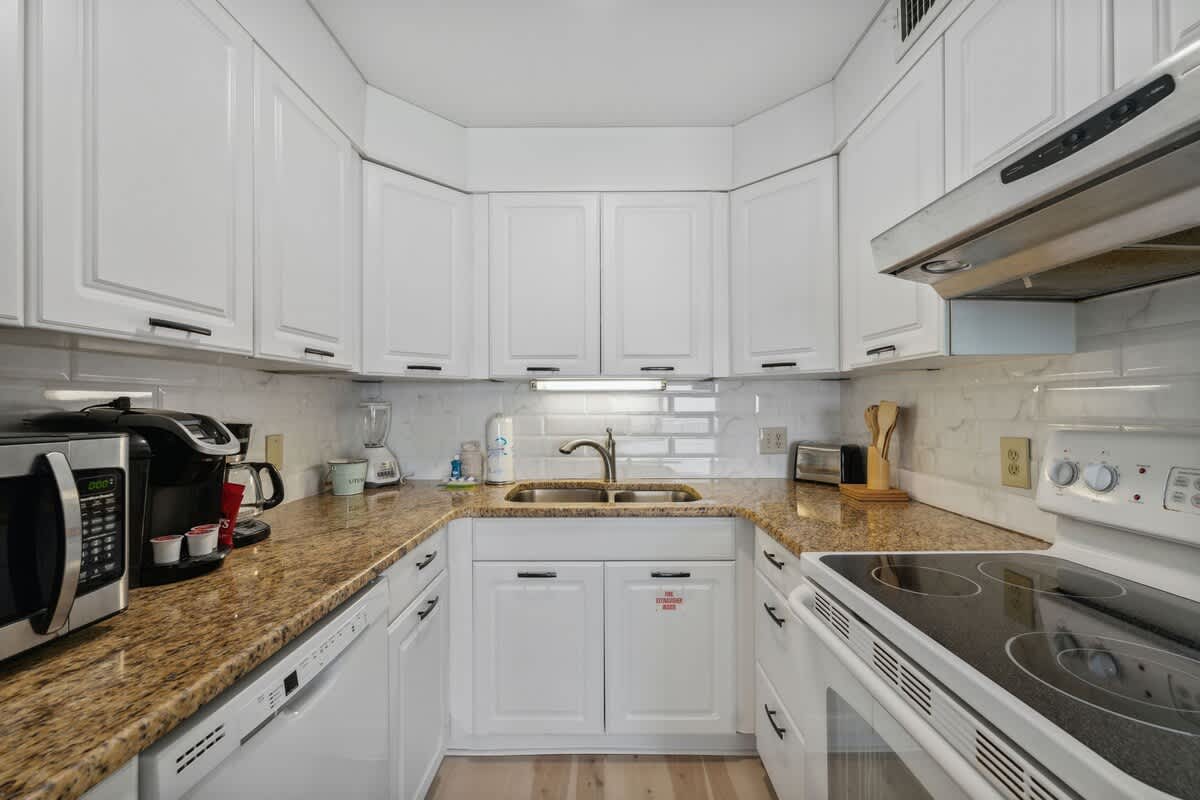 The Summit 1222 – Kitchen with white cabinets, granite countertops, and stainless steel appliances.