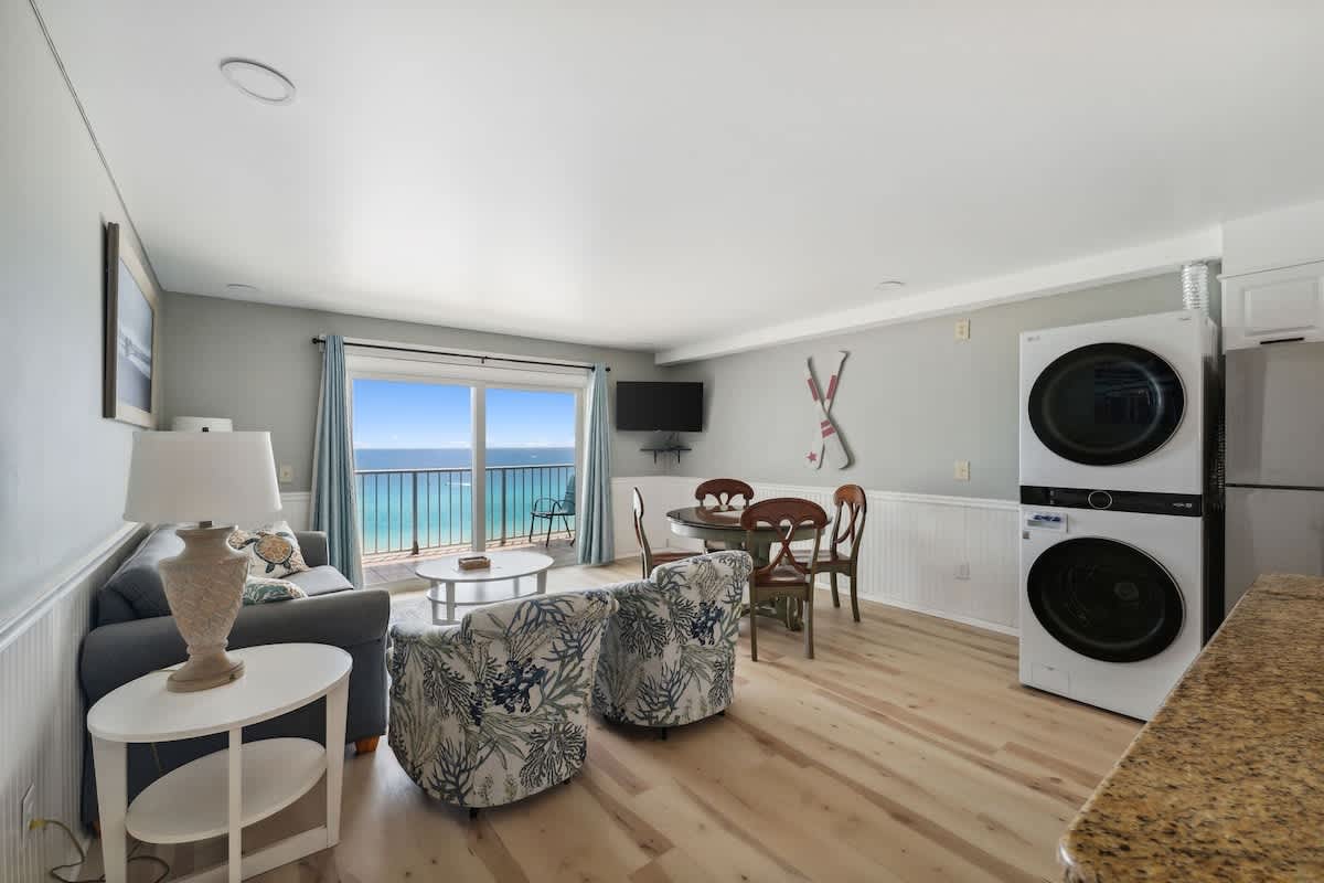 The Summit 1222 – Living area with ocean view, dining table, washer-dryer, and seating area with sofa and chairs.