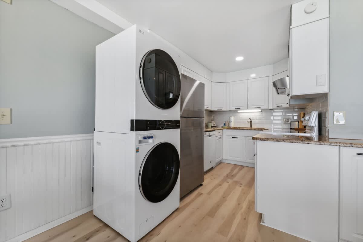 The Summit 1222 – Modern kitchen with washer and dryer, stainless steel refrigerator, and white cabinetry.