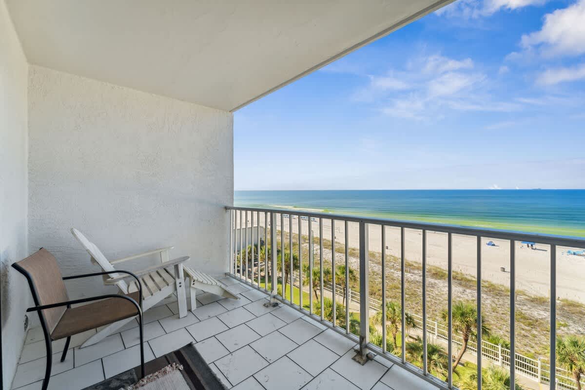 The Summit 725 – Balcony view overlooking the beach and ocean with two chairs on tiled floor.