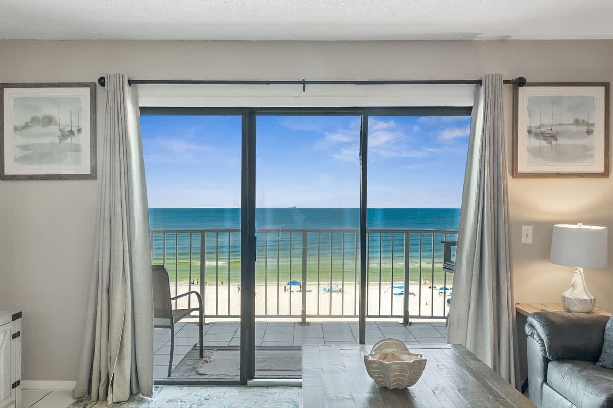 The Summit 725 – Living room with ocean view through large sliding glass doors, beach visible below.