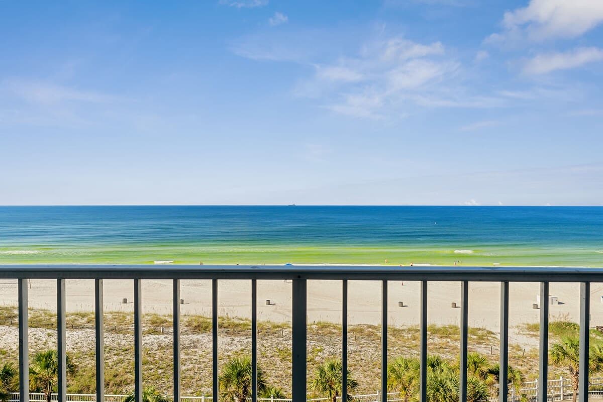 The Summit 725 – View from balcony overlooking sandy beach and ocean with clear blue sky.
