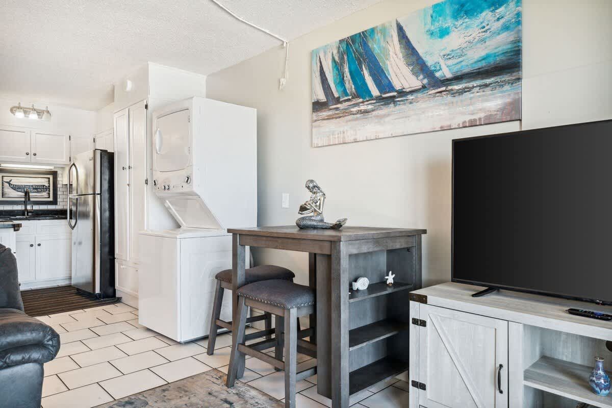 The Summit 725 – Cozy living area with a washer-dryer, small dining table, and a TV.