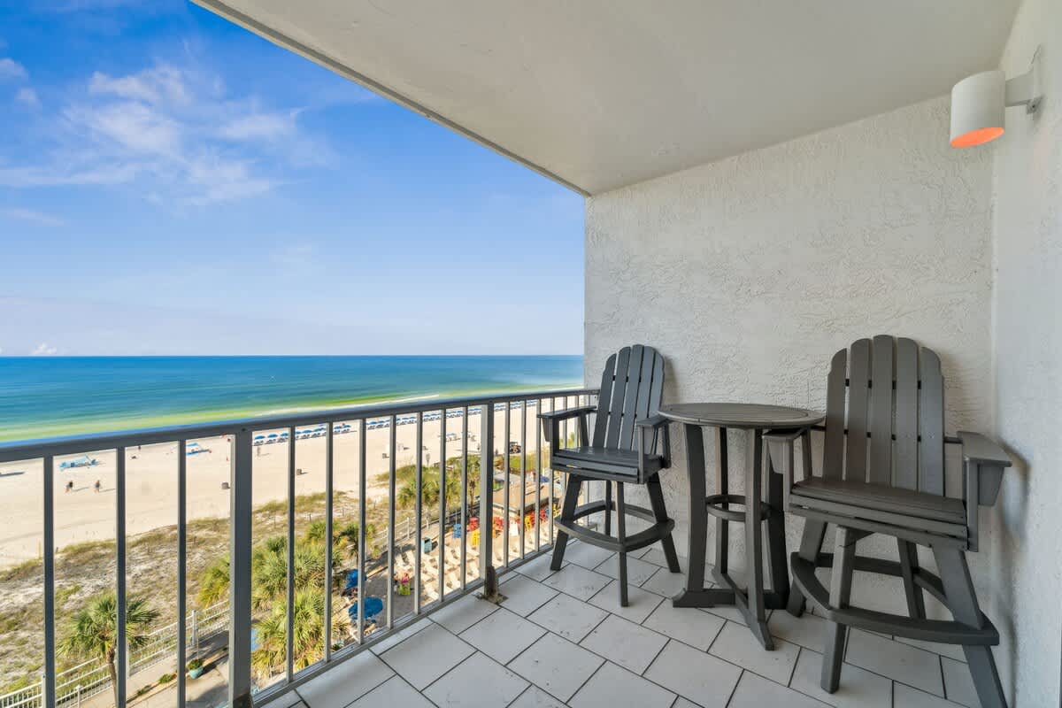 The Summit 725 – Balcony with two high chairs and a table overlooking the beach and ocean.