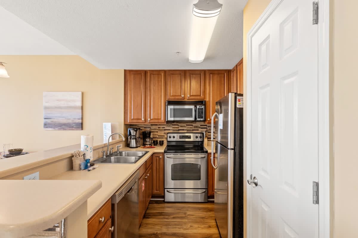 Seychelles 205 – Kitchen with wooden cabinets, stainless steel appliances, and a countertop bar area.