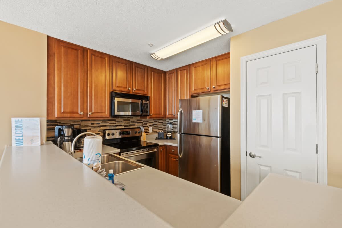 Seychelles 205 – Modern kitchen with wooden cabinets, stainless steel appliances, and a light countertop.
