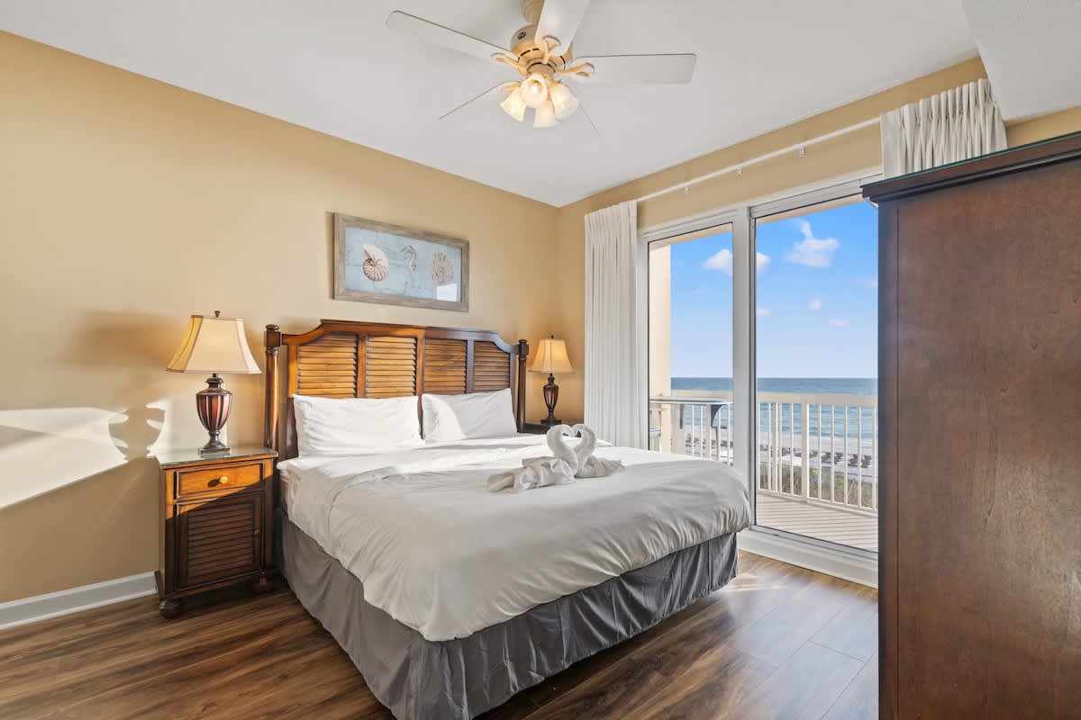 Seychelles 205 – Bright bedroom with ocean view, king bed, bedside lamps, and wooden furniture.
