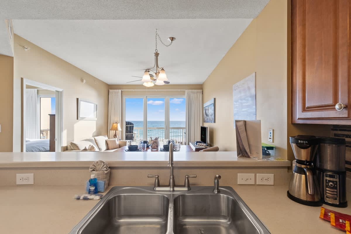Seychelles 205 – Open-plan living area with kitchen, ocean view, and patio access.