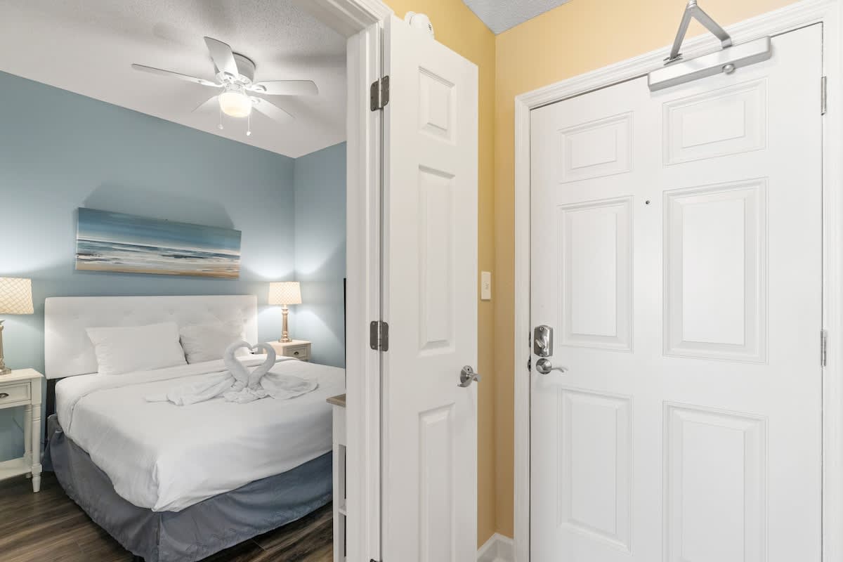 Seychelles 205 – Bedroom with blue walls, double bed, nightstands, and decorative towels shaped as swans.
