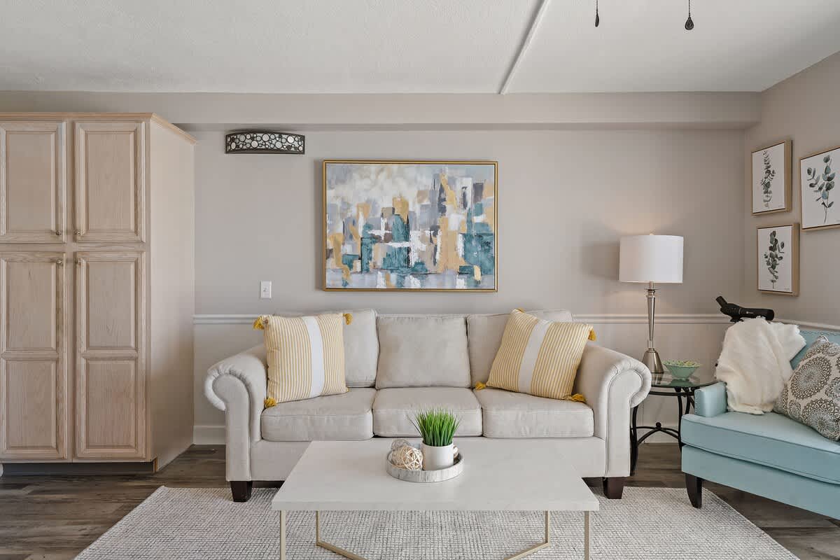 The Summit 919 – Living room with beige couch, aqua chair, coffee table, artwork, and decorative accents.