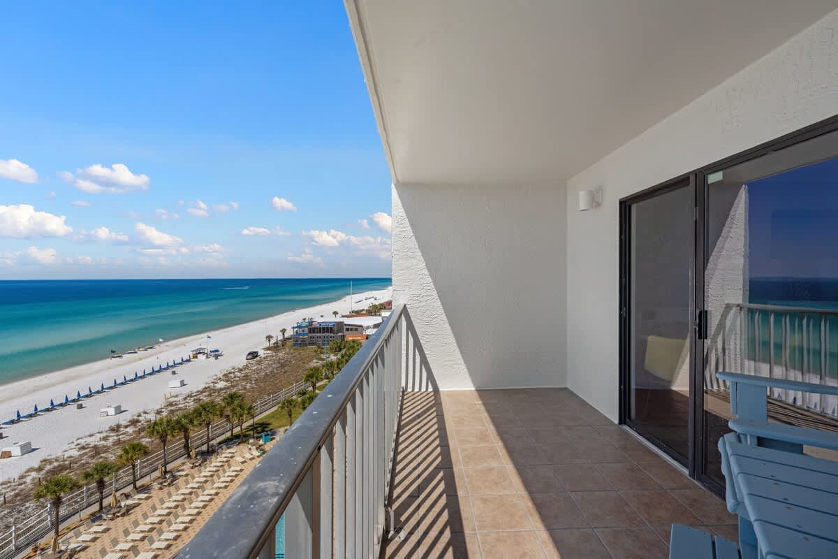The Summit 919 – Balcony overlooking sandy beach and turquoise ocean with chairs and tiled flooring.