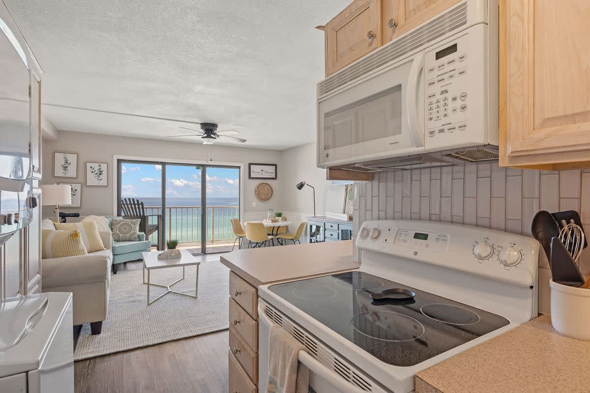 The Summit 919 – Living room with kitchen, ocean view, dining area, couch, and light-colored decor.